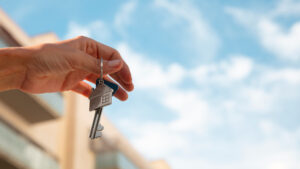 mano sosteniendo llave de casa con fondo de cielo